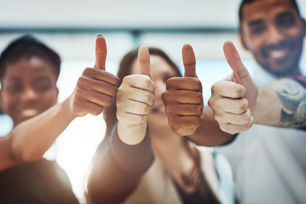 4 office workers giving thumbs up at work