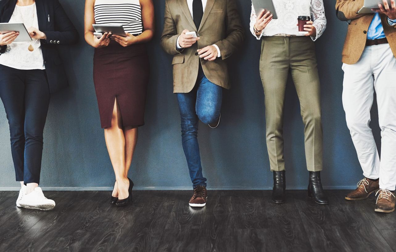 Cropped studio shot of a group of businesspeople using wireless technology while waiting in line against a gray background