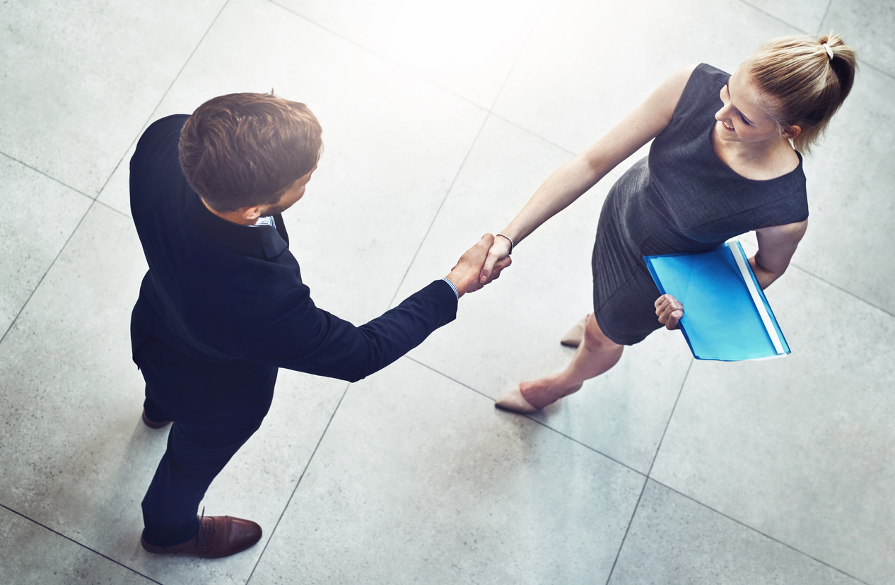 High angle shot of two unrecognizable businesspeople shaking hands in a corporate office