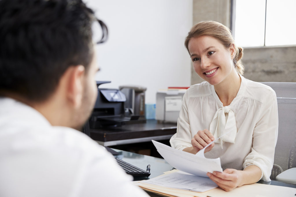Smiling white female professional in meeting or job interview with young man looking at soft skills