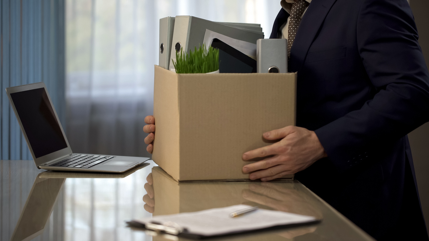 Employee putting his stuff from work desk in carton box, leaving job, high turnover concept