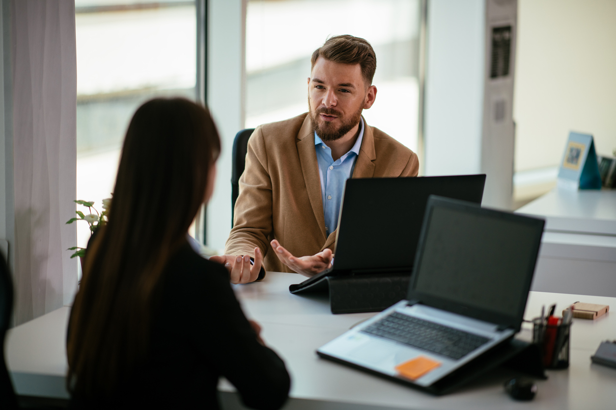 Colleagues talking to each other in the office about high turnover rates.