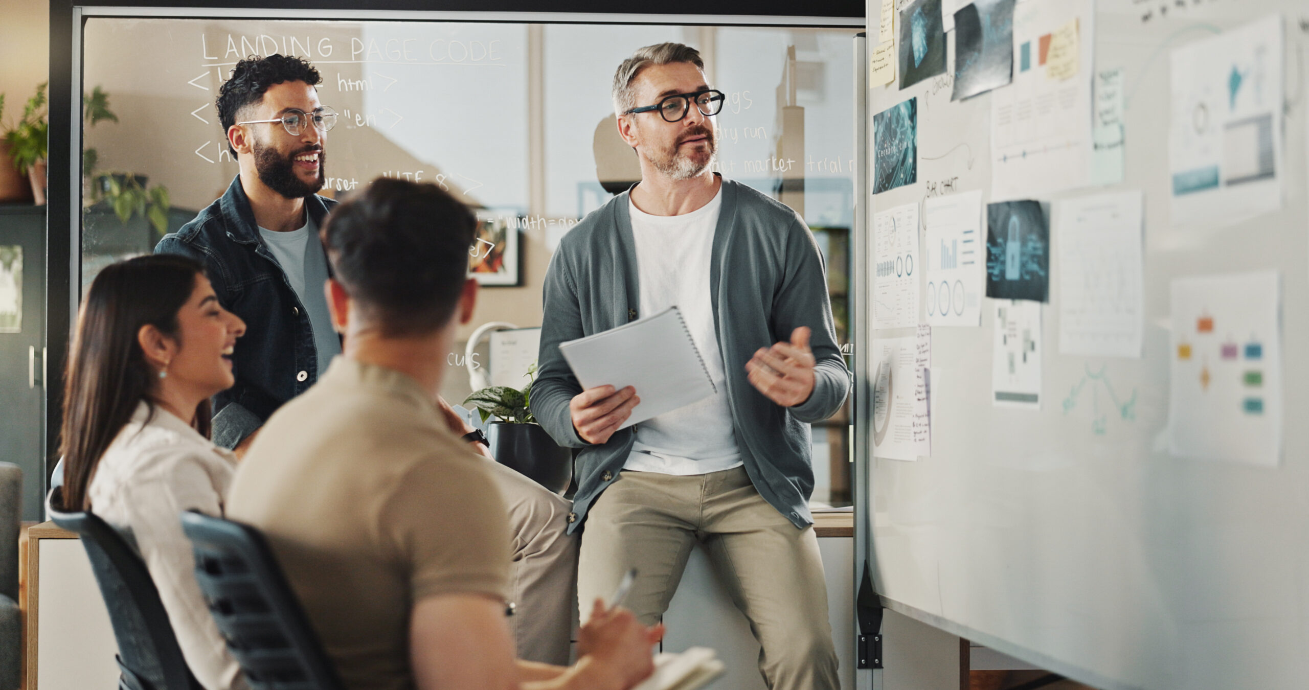 group of people in front of a whiteboard with charts