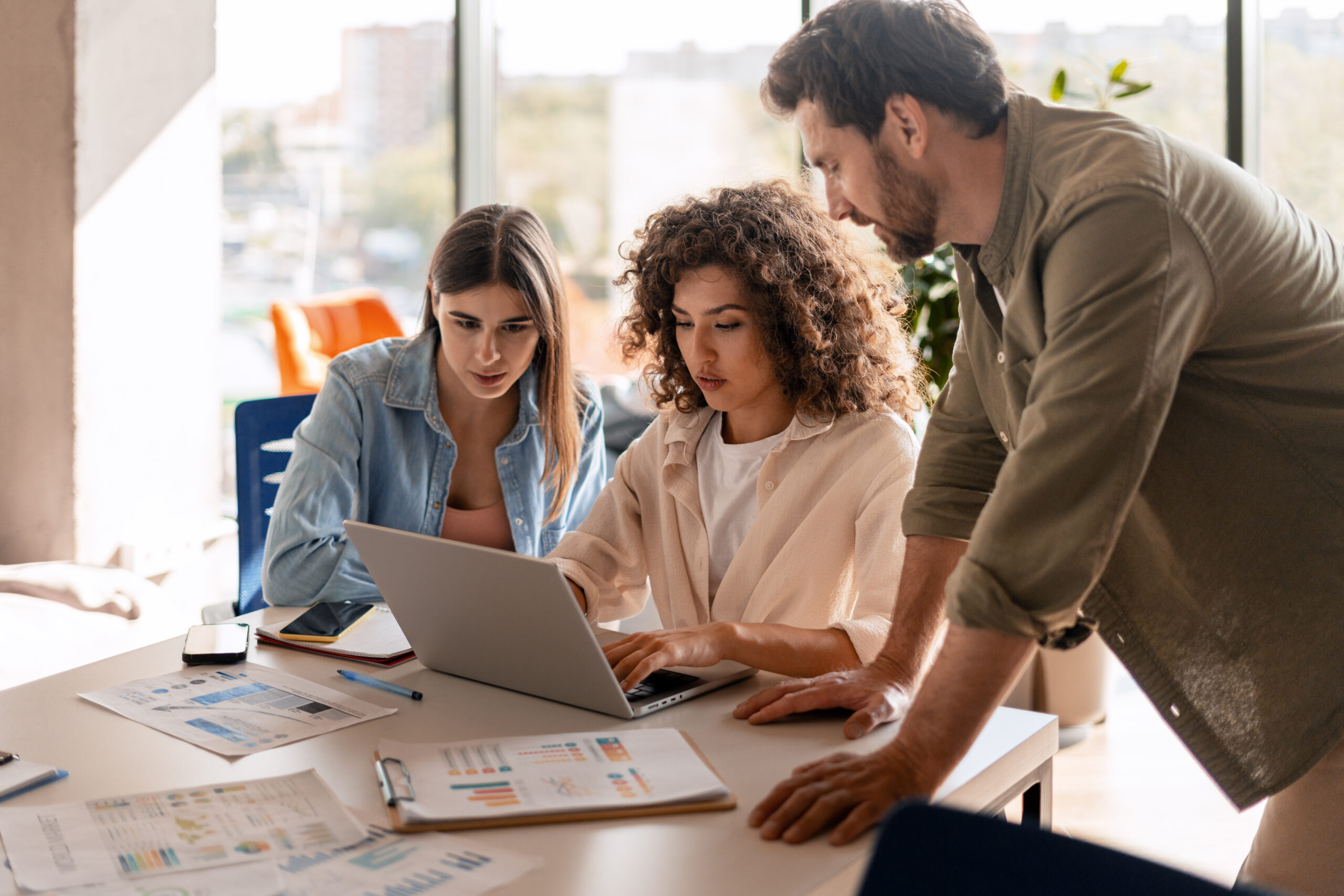 Marketing team analyzing data and collaborating on laptop in office meeting