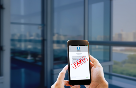 A cell phone is being held up with the warning "fake".