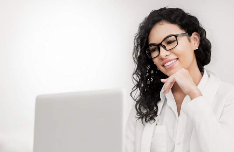 A woman is looking at her computer smiling, about to write a thank you letter to the hiring manager she just interviewed with.